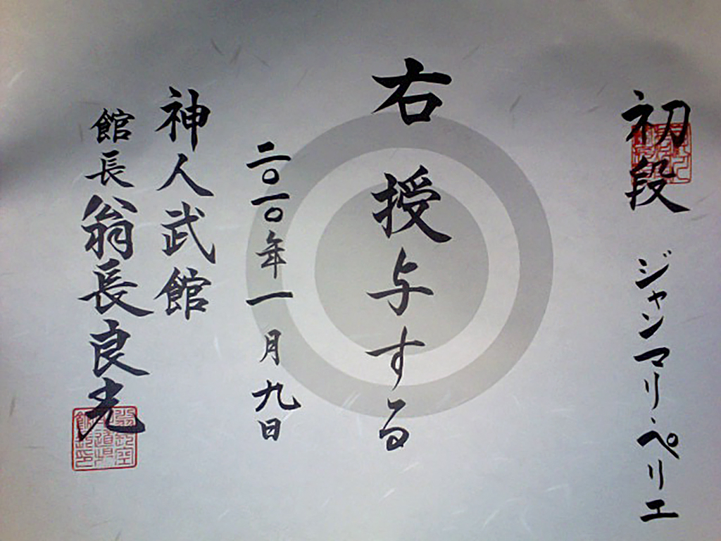 <em>La personne mentionnée à droite se voit attribuer le rang indiqué. Donné le 5 janvier 2010.<br>
Shinjinbukan. Kanchō, Onaga Yoshimitsu</em><br>
<strong>Sho Dan, Jean-marie PERRIER</strong>