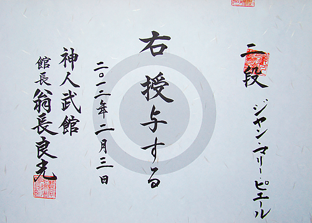 <em>La personne mentionnée à droite se voit attribuer le rang indiqué. Donné le 3 février 2012.<br>
Shinjinbukan. Kanchō, Onaga Yoshimitsu</em><br>
<strong>Ni Dan, Jean-marie PERRIER</strong>